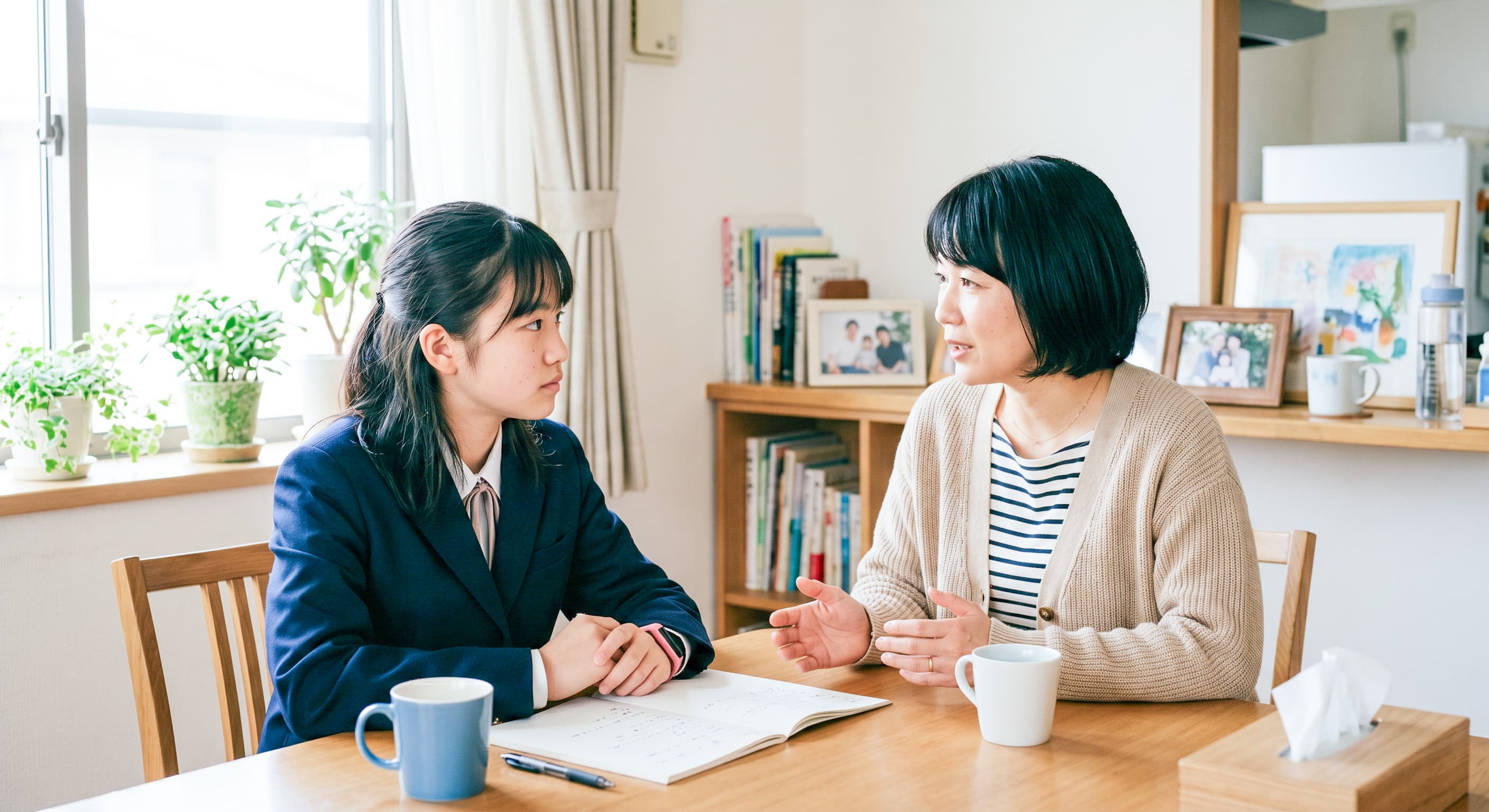 制服を着た生徒と保護者が食卓で話し合う様子